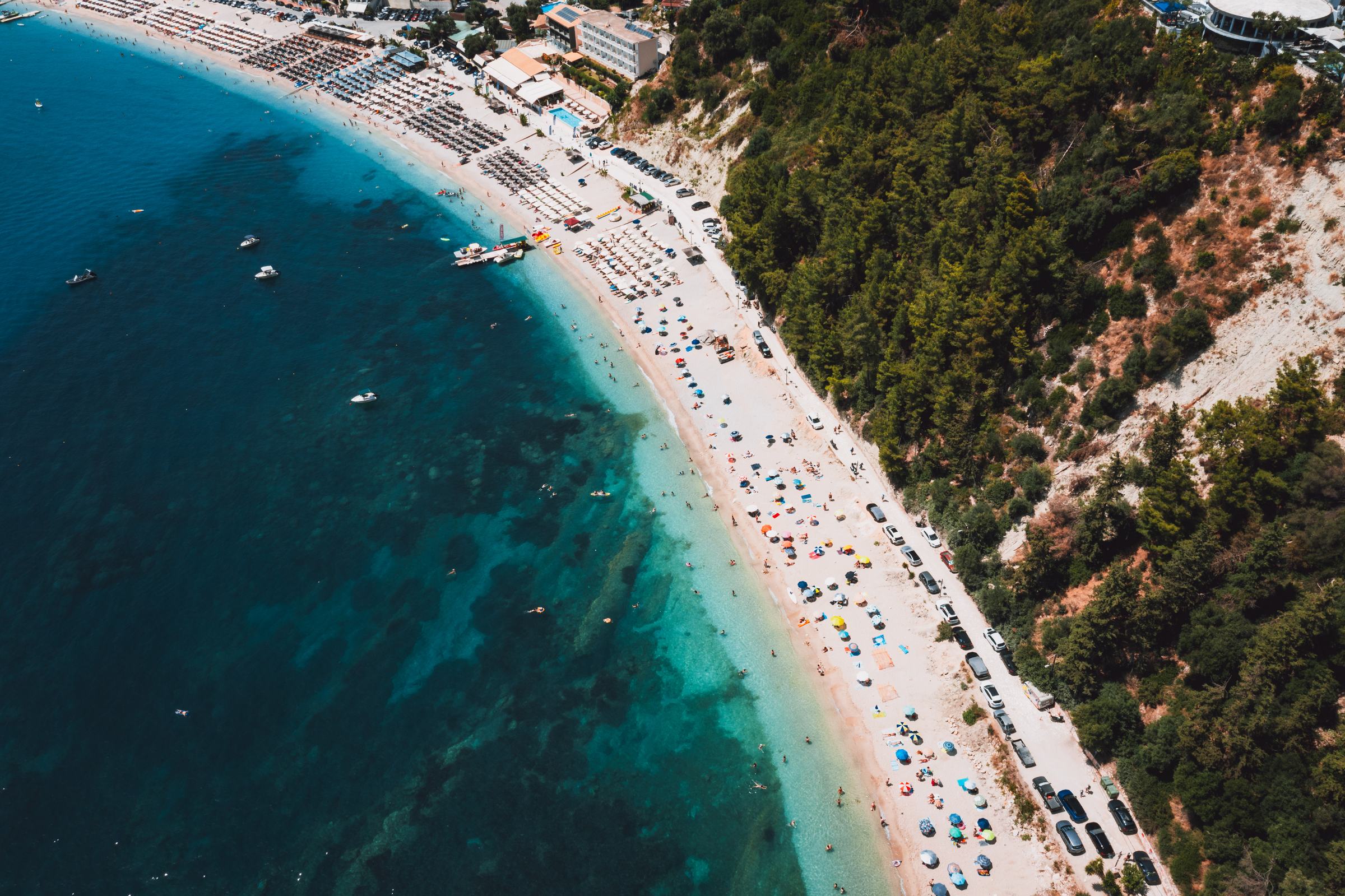 The curve of a beach where turquoise shallows meet deep water.