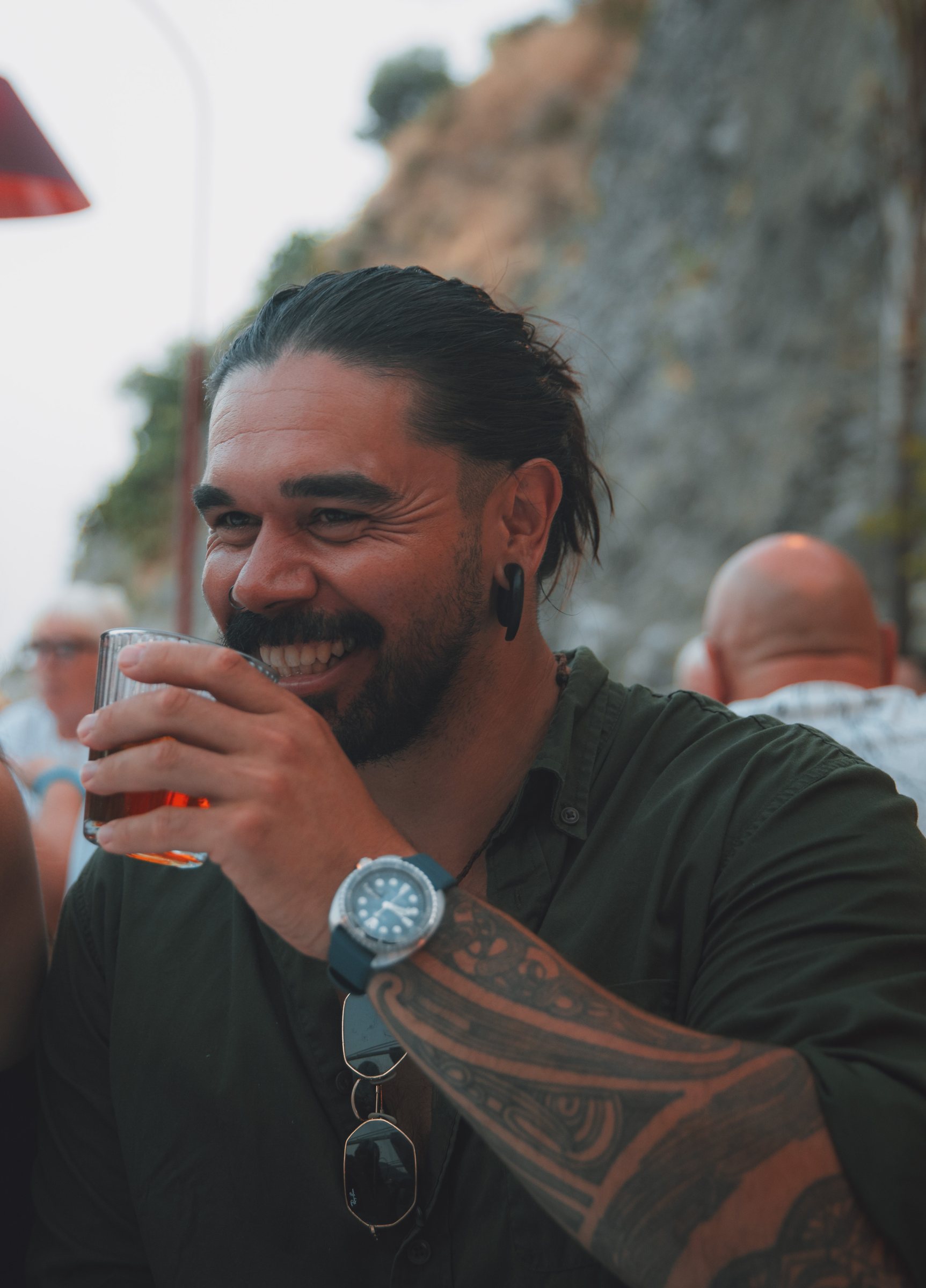 Laughing at a harbourside table, warm lights blurred behind.